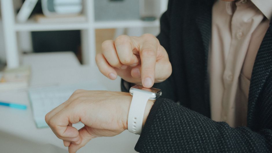 A man in a suit interacts with a smartwatch, using touch technology in a modern office.