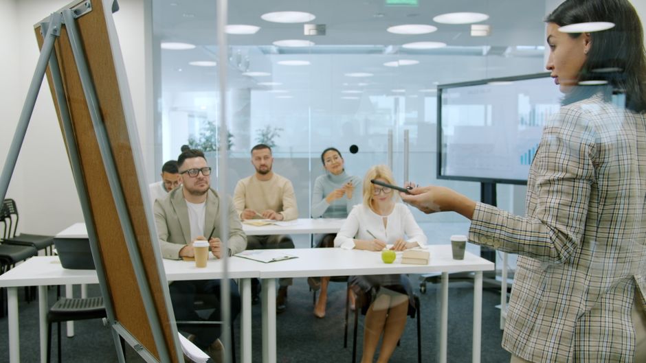 Business team attending a presentation in a glass-walled conference room.