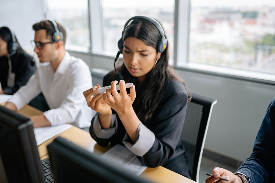 Call center agent using headset in a bright office setting, focused on task.